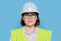 Female industrial worker in protective hard hat and vest on blue background Royalty Free Stock Photo