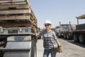 Female industrial worker standing by flatbed truck in timber yard Royalty Free Stock Photo