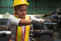 Female industrial worker working and checking machine in a large industrial factory with many equipment