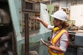 Female industrial worker working and checking machine in a large industrial factory with many equipment