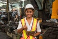 Female industrial worker working and checking machine in a large industrial factory with many equipment