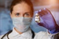 Female doctor holding in hand in disposable medical glove a coronavirus vaccine