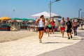 Female instructor and group of people running at a beach path outdoors.