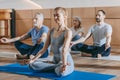 female instructor with senior people sitting in lotus position on yoga