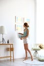Female interior designer decorating white wall with pictures Royalty Free Stock Photo