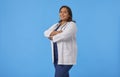 Female internist with her arms crossed smiling looking at the camera against a blue background