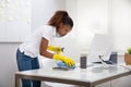 Female Janitor Cleaning Desk In Office Royalty Free Stock Photo