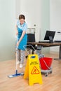 Female Janitor Cleaning Hardwood Floor In Office