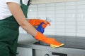 Female janitor cleaning kitchen stove with rag Royalty Free Stock Photo