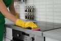 Female janitor cleaning kitchen stove with sponge Royalty Free Stock Photo