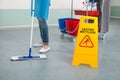 Female Janitor Mopping Corridor With Caution Sign Royalty Free Stock Photo