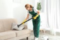 Female janitor removing dirt from sofa cushion