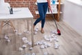 Female Janitor Sweeping Crumbled Paper On Floor