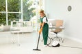 Female janitor in uniform cleaning floor