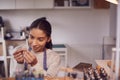 Female Jeweller At Bench Checking Ring She Is Working On In Studio