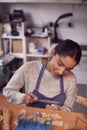 Female Jeweller At Bench Working On Ring With File In Studio