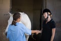 Female jockey giving handshake to vet by horse Royalty Free Stock Photo