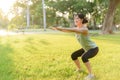 Female jogger. Fit young Asian woman with green sportswear squatting in park before running and enjoying a healthy outdoor. Royalty Free Stock Photo