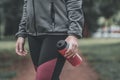 Female jogger holding bottle of refreshing strawberry juice in park