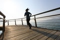 Female jogger morning exercise on seaside boardwalk during sunrise Royalty Free Stock Photo