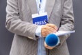 Female journalist at news conference or media event, writing notes, holding microphone Royalty Free Stock Photo