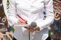 Female journalist at news event, writing notes, holding microphone