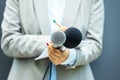 Female journalist at press conference, writing notes, holding microphone. Freedom of the media concept. Royalty Free Stock Photo