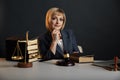 Female jurist isolated at the dark background. Books and gavel with justice scales.