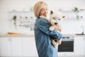 Female keeper holding dog on shoulder in room interior