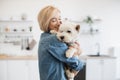 Female keeper holding dog on shoulder in room interior