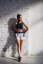 Female kickboxer standing in a boxing studio while dust particles flies in sunflare light background.