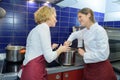 Female kitchen staff chatting while preparing food in saucepans