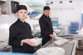 Female kitchen worker arranging cleaned dishes