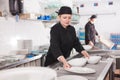 Female kitchen worker arranging cleaned dishes