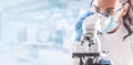 Female lab technician in protective glasses, gloves and face mask sits next to a microscope in laboratory Royalty Free Stock Photo