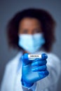 Female Lab Worker in Lab Coat And Face Mask Researching Omicron Variant Of Covid-19 Holds Test Tube Royalty Free Stock Photo