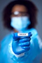 Female Lab Worker in Lab Coat And Face Mask Researching Omicron Variant Of Covid-19 Holds Test Tube Royalty Free Stock Photo