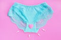 Female lace blue panties with a pink heart and spermatozoa on a pink background.