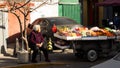 Female with a large wheeled shopping cart resting on a public sidewalk in Beijing