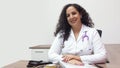 Female latin female doctor sitting smiling in her office with stethoscope on her neck