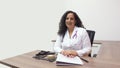 Female latin female doctor sitting smiling in her office with stethoscope on her neck