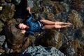 Female laying on sea rock. Lady in wet blue dress. Summer time and relax. Beach vacation. Relaxation and meditation Royalty Free Stock Photo