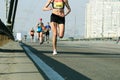 Female leader athlete runner running city marathon. Young woman running on city bridge road. Marathon running in the morning