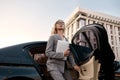 Female leader. Young beautiful business woman in stylish suit holding laptop and getting out of a black car. Business Royalty Free Stock Photo