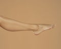 Female leg and foot isolated on beige background
