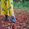 Female leg / foot walking in autumn leaves: floral ankle boot and yellow flares