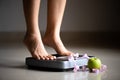 Female leg stepping on weigh scales with measuring tape and green apple. Healthy lifestyle, food and sport concept Royalty Free Stock Photo