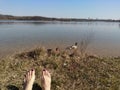 Female legs barefoot relaxing on a lake shore spring landscape Royalty Free Stock Photo