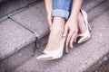 Female legs in a beautiful peach high-heeled shoes with gold nose. close-up. hands corrected jeans.