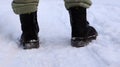 Female legs in black boots, winter walk in the snow. Active woman walking away from the camera in the winter forest. Focus on your Royalty Free Stock Photo